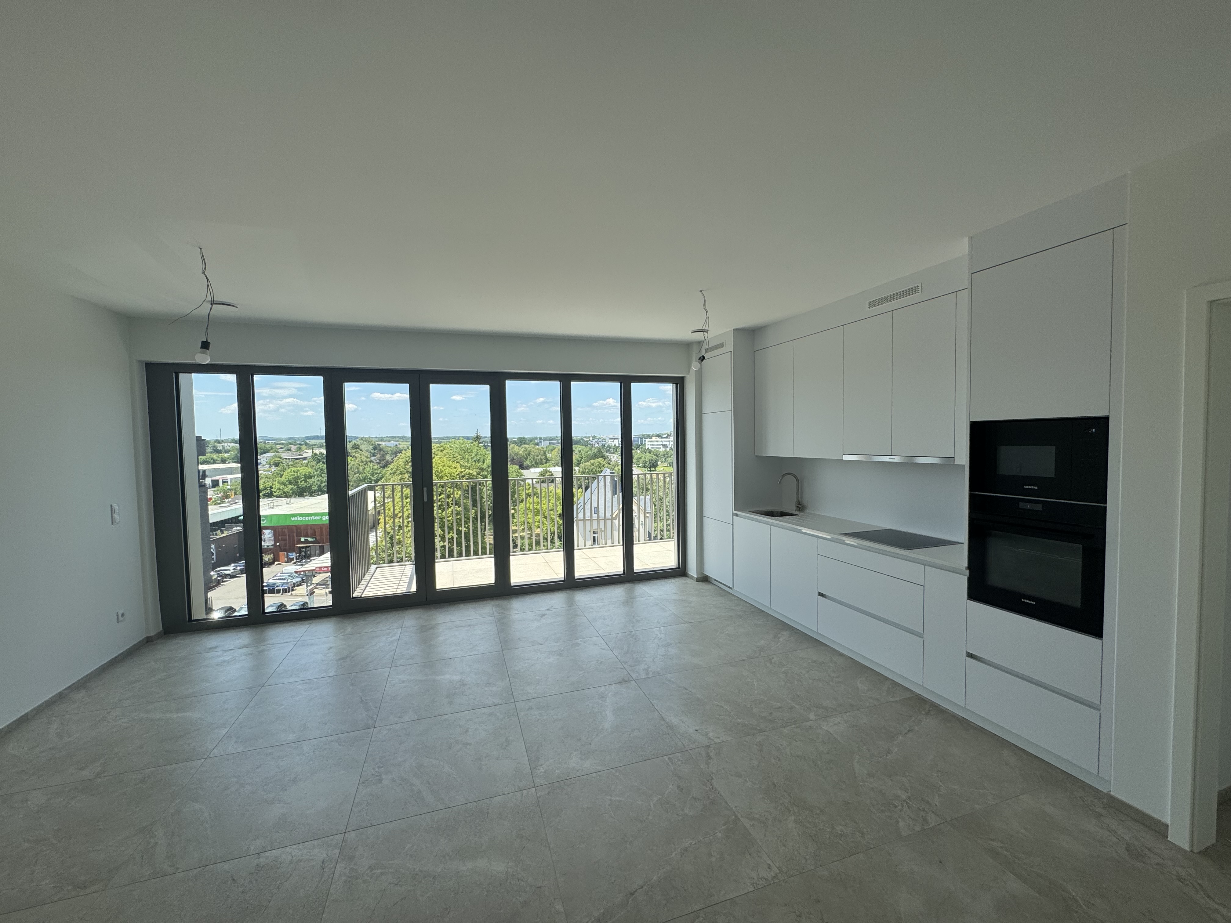 Intérieur moderne d'un appartement avec cuisine ouverte blanche et grandes baies vitrées