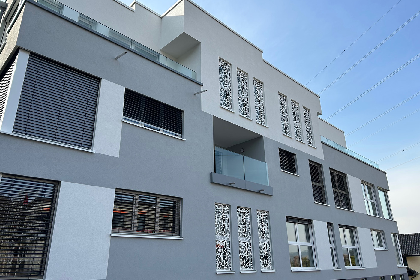 Façade avant d’un immeuble résidentiel moderne avec balcons en verre à Heisdorf